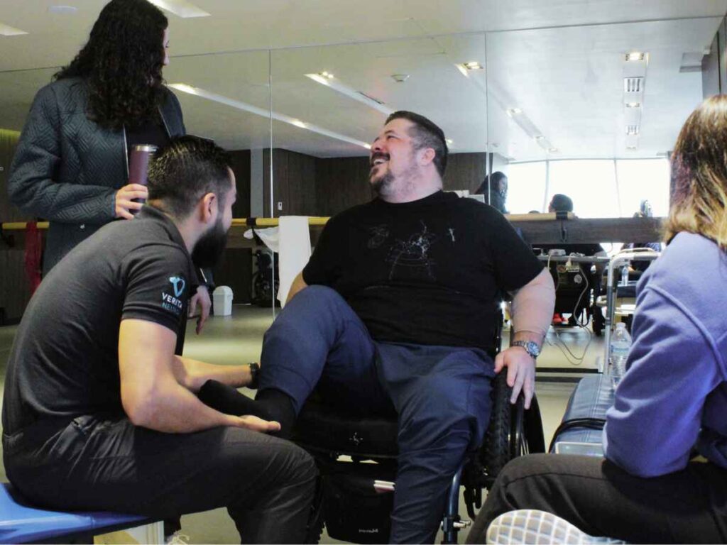 Paul, a recovery patient from a motorcycle accident spinal injury, actively engages in rehabilitation exercises under the guidance of a professional healthcare team at Verita Neuro Mexico in a well-equipped therapy room