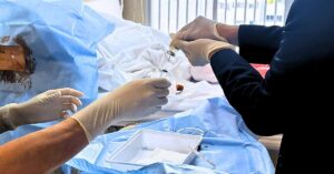 The image depicts a healthcare professional preparing a stem cell injection for a lumbar puncture treatment. The patient's back is exposed as the healthcare professional holds a syringe, ready to administer the Stem Cell treatment. The medical setting is calm and sterile, emphasizing the precision and care involved in delivering this regenerative treatment.