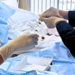 La imagen muestra a un profesional de la salud preparando una inyección de células madre para un tratamiento de punción lumbar. La espalda del paciente está expuesta mientras el profesional sostiene la jeringa, listo para administrar la terapia regenerativa. El ambiente médico es sereno y estéril, subrayando la precisión y el cuidado requeridos en la aplicación de este tratamiento avanzado.