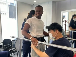 Patient Story Profile Picture - Davonta, a spinal cord injury patient practicing assisted standing therapy with parallel bars at Verita Neuro